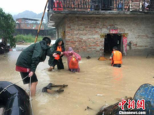 在齊大腿深的水中,，消防官兵扶著受災(zāi)民眾趟過(guò)深水區(qū)。消防供圖