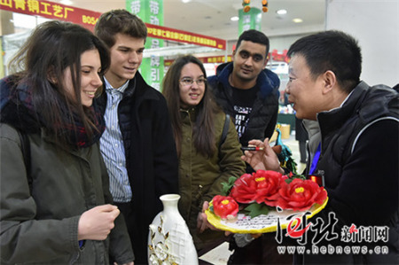 一位陶瓷商正向幾名來(lái)自石家莊四十二中的外國(guó)留學(xué)生介紹中國(guó)傳統(tǒng)節(jié)日飾品牡丹瓷,。