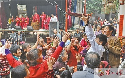 青年男子用托盤(pán)端紅豆腐丸,，供村民爭(zhēng)搶,。