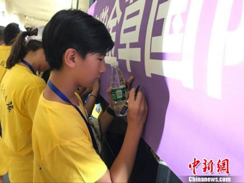 華裔師生在“不忘歷史珍愛和平——南京紫金草國際和平學院海外華裔青少年寄語留言”橫幅上簽名。江蘇省僑辦 華裔師生在“不忘歷史珍愛和平——南京紫金草國際和平學院海外華裔青少年寄語留言”橫幅上簽名,。江蘇省僑辦