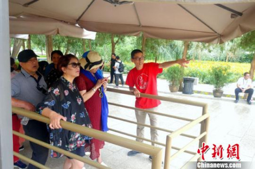 圖為志愿者為等候參觀的游客介紹莫高窟景區(qū)相關(guān)內(nèi)容?!±钗某?攝 圖為志愿者為等候參觀的游客介紹莫高窟景區(qū)相關(guān)內(nèi)容,?!±钗某?攝