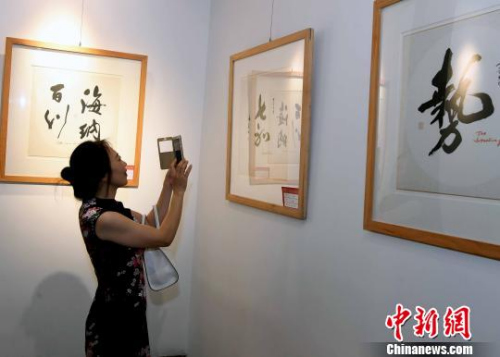 一名女性觀眾用手機拍攝參展書法作品,。　記者劉可耕 攝