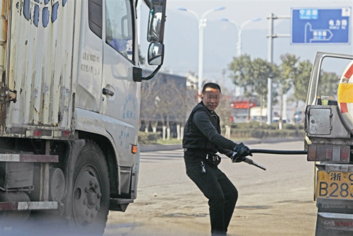 拔槍加油一名男子從油罐車(chē)上拔出加油槍?zhuān)瑴?zhǔn)備給貨車(chē)加油 拔槍加油一名男子從油罐車(chē)上拔出加油槍?zhuān)瑴?zhǔn)備給貨車(chē)加油