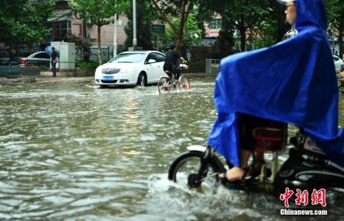 7月16日,，河北石家莊一條馬路積水嚴(yán)重，民眾涉水騎行,。當(dāng)日,，該省氣象臺(tái)發(fā)布暴雨藍(lán)色預(yù)警，多地遭受暴雨襲擊,。<a target='_blank' >中新社</a>記者 翟羽佳 攝