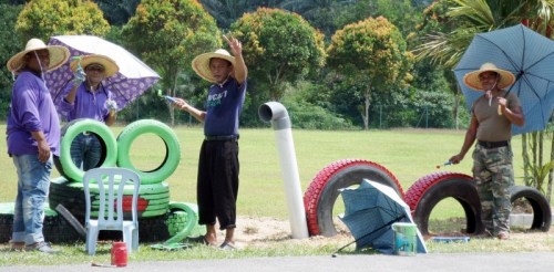 大家戴著草帽,、撐著傘，在烈日下美化校園,。（馬來(lái)西亞《星洲日?qǐng)?bào)》）