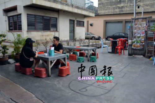 在祖屋前,，與三兩好友蹲坐小凳存吃著鮮蛤，別具風(fēng)味,。(馬來西亞《中國報》記者 趙詩綺 攝)