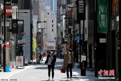 日本東京，戴口罩的女士走過空無一人的購物區(qū),。