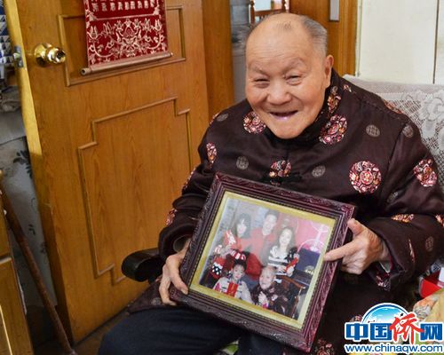 中國僑網(wǎng)家住北京東城區(qū)體育館路街道的九旬僑眷老人房仲孝向記者展示他和兒孫的合影,。楊凱淇 攝