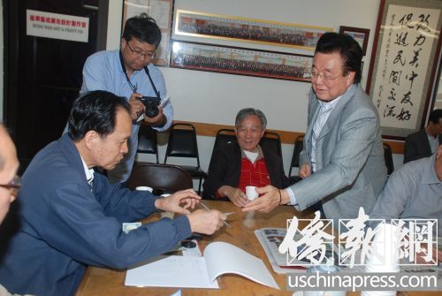 吳國(guó)寶向華商總會(huì)辦公室主任雷榮暢遞交其捐款支票,。(美國(guó)《僑報(bào)》/吳卓明