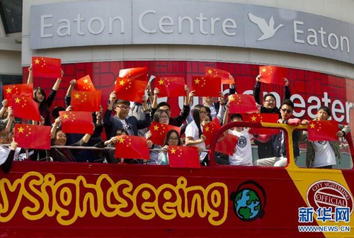 中國(guó)僑網(wǎng)9月16日,,在加拿大多倫多鄧達(dá)斯廣場(chǎng),演唱會(huì)參與者在??坑诼愤叺囊惠v觀光車(chē)上手持五星紅旗演唱并合影,。(新華社/鄒崢 攝)