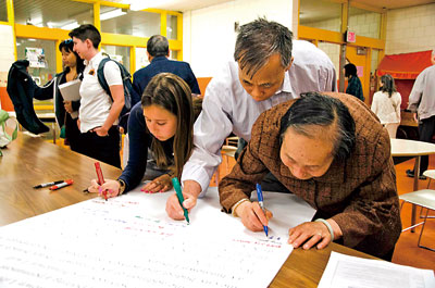 中國僑網(wǎng)到會人員在圖書館倡議板上簽字以示支持,。右數(shù)第三為市議員Michael Flaherty辦公室的政策主管Robyn Casper。(美國《星島日報》)