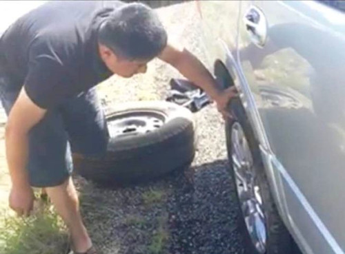 休斯敦華人高速路駕車行駛時,車胎被流彈打爆,。圖為華人在更換輪胎,。(美國《世界日報》)