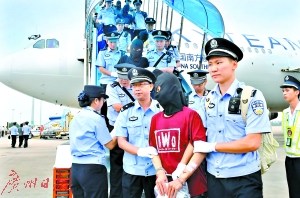 129名電信詐騙犯罪嫌疑人在民警押解下走下飛機(jī)。