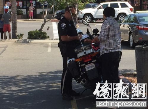 警察正在阿旺戴爾路旁的香港超市停車場給一個華裔路人開罰單,。(美國《僑報》/高睿