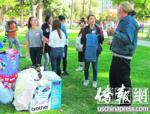 華裔志愿者捐贈衣服給有需要的人,并細心地幫助他們挑選合適尺碼,。(美國《僑報》/翁羽
