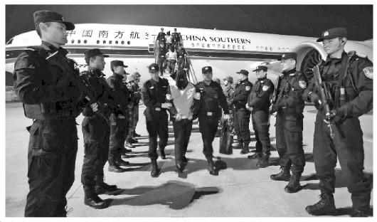 中國僑網(wǎng)圖為警方押解嫌疑人下飛機(jī),。張偉 攝