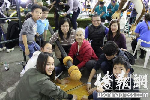 中國(guó)僑網(wǎng)趙奶奶(紅衣)和她的一家三代在為金箍棒涂膠粘貼草籽。(美國(guó)《僑報(bào)》/高睿 攝)