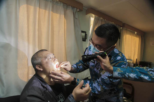 中國僑網(wǎng)兩位軍醫(yī)檢查患者咽部情況,。
