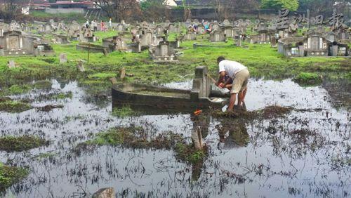中國僑網(wǎng)市民被迫在猶如水中小島的義山山頭祭拜先人,非常狼狽及不便,。(圖:星洲日報(bào))