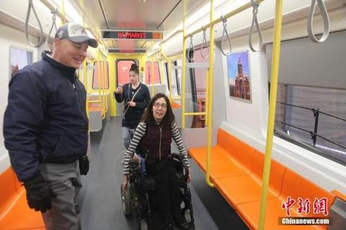 中國僑網(wǎng)資料圖:4月3日,,由中國中車集團(tuán)為美國波士頓設(shè)計(jì)建造的橙線地鐵實(shí)車模型在波士頓市政廳廣場與當(dāng)?shù)毓娨娒妗D為現(xiàn)場一位殘障人士在實(shí)車模型車廂內(nèi)參觀體驗(yàn),。中新社記者 馬德林 攝