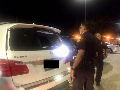 中國僑網(wǎng)糖城警局警員在受害華女被打碎后車窗的奔馳SUV旁展開調(diào)查。(陳女士提供圖片)