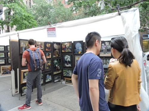 中國僑網(wǎng)華裔情侶在展銷會上相中畫作,,商量要否購買回家,。(美國《世界日報(bào)》/王靖雯 攝)