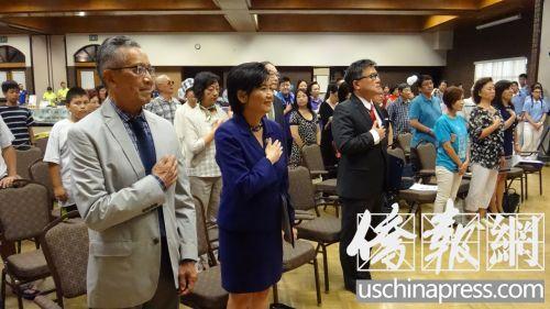 中國僑網(wǎng)(前排從左至右)唐廷贊,、趙美心,、江俊輝和上百名與會者向國旗致敬,。(美國《僑報》/高睿 攝)