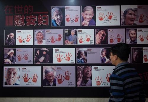 中國僑網(wǎng)資料圖片:2016年12月10日,一名與會(huì)者在觀看紀(jì)實(shí)畫冊(cè)《90位幸存慰安婦實(shí)錄》首發(fā)現(xiàn)場(chǎng)展示的書中照片,。新華社記者 羅曉光 攝