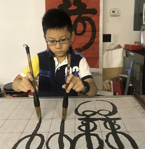 中國(guó)僑網(wǎng)于昊辰小小年紀(jì)喜愛(ài)雙手書(shū)法,,以此了解和學(xué)習(xí)中國(guó)文化,。(美國(guó)《世界日?qǐng)?bào)》/劉大琪 攝)