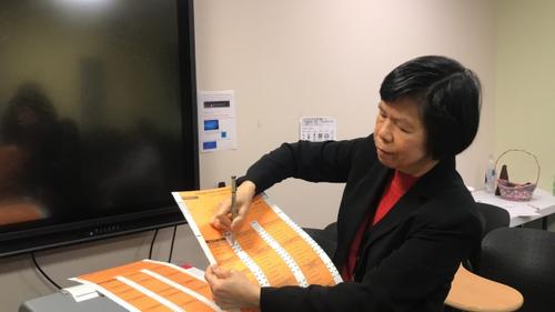 中國(guó)僑網(wǎng)美國(guó)芝加哥選舉委員會(huì)外展主任劉珍演示用紙投票的勾選方式,。(美國(guó)《世界日?qǐng)?bào)》/董宇 攝)