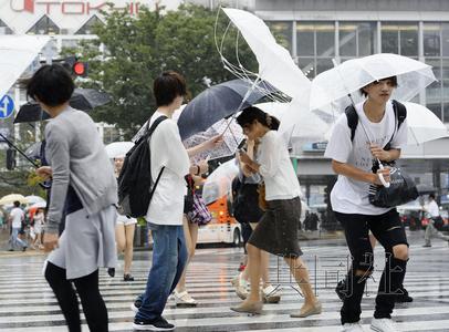 圖為在臺風“蒲公英”強風中緊持雨傘步行的人們,。8月22日下午攝于東京澀谷,。(日本共同社)