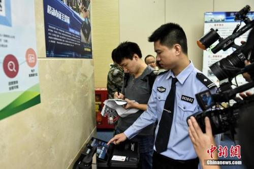 中國僑網(wǎng)資料圖:警方演示出入境證件移動服務辦證機工作流程,。中新社記者 陳驥旻 攝