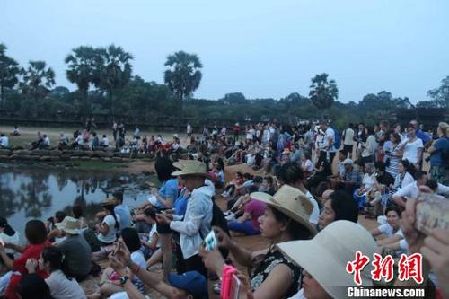 中國僑網(wǎng)資料圖:國際游客守候在吳哥窟景區(qū)觀看日出,?!×蚊艏选z