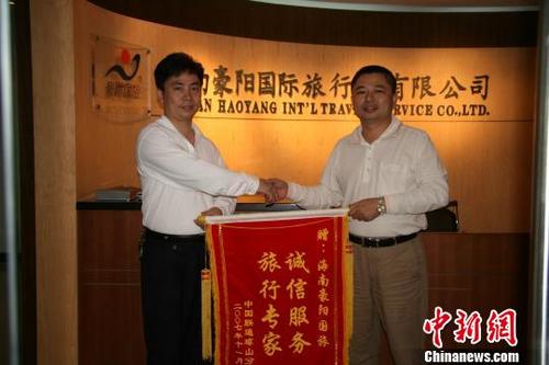 中國僑網(wǎng)圖為客戶向梁昌斌(右)贈送錦旗。豪陽國旅 供圖
