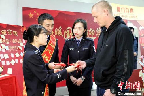 中國僑網澳大利亞旅客特拉維斯先生(右)成為廈門口岸144小時過境免簽政策實施一年來第1000名旅客,。供圖