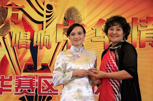 中國(guó)僑網(wǎng)評(píng)委王穎老師為Akela頒發(fā)精美冠軍獎(jiǎng)杯,。(丁玎 攝)