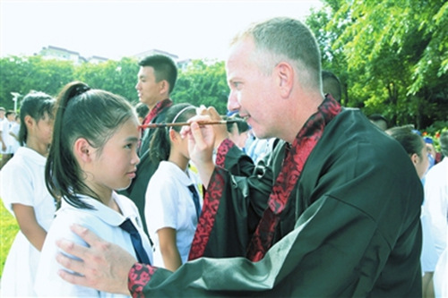 海南華僑中學(xué)三亞學(xué)校,,一名身著傳統(tǒng)漢服的外籍老師正在給學(xué)生點朱砂啟智開蒙。(本報記者