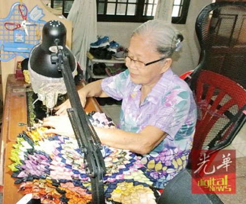 李美齡戴著老花鏡,踩著老針車,,手工制作環(huán)保手提袋及地墊,。(馬來西亞《光華日報》)