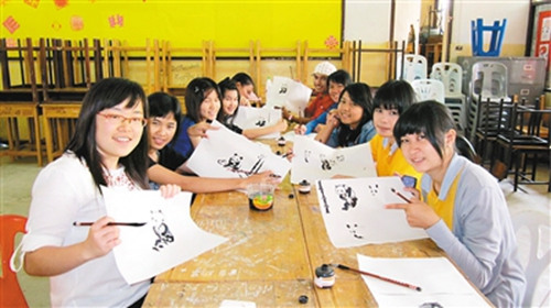 梁貞(左一)給泰國學(xué)生教畫大熊貓,。