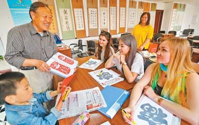 中國僑網(wǎng)圖為秦皇島市海港區(qū)燕大西苑社區(qū)居民教外國留學生學習剪紙,。 本報記者 史自強攝