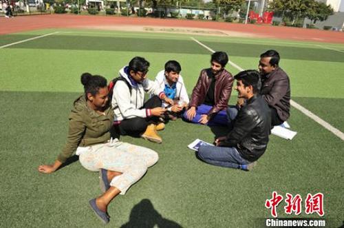 中國僑網(wǎng)課間,留學(xué)生在足球場交流,?!】到帧z