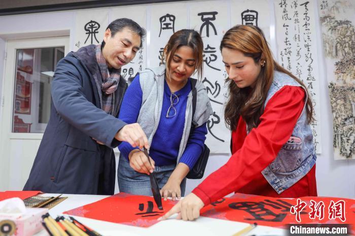 中國僑網(wǎng)外國友人向老師學(xué)習(xí)毛筆書法,。張鷹 攝