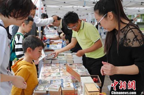 中國僑網(wǎng)資料圖:“世界讀書日”民眾在上海徐匯濱江感受都市閱讀文化. 家長帶著孩子在現(xiàn)場挑選自己喜愛的書籍,。 殷立勤 攝
