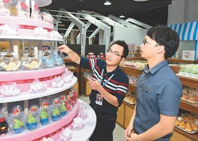 中國僑網(wǎng)臺灣青年創(chuàng)業(yè)者曾翊展(左)在廈門“寶島夢工廠”里指導(dǎo)員工擺設(shè)商品,。 新華社記者 姜克紅攝