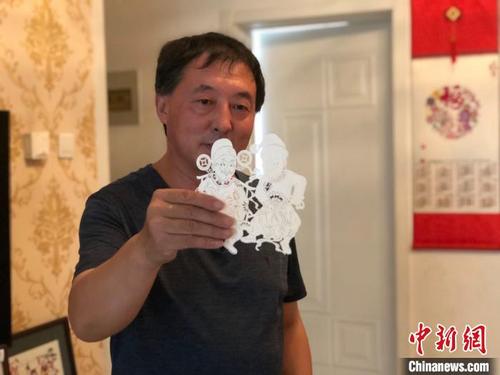 中國僑網(wǎng)李寶峰在展示剪紙作品,?!『聼睢z