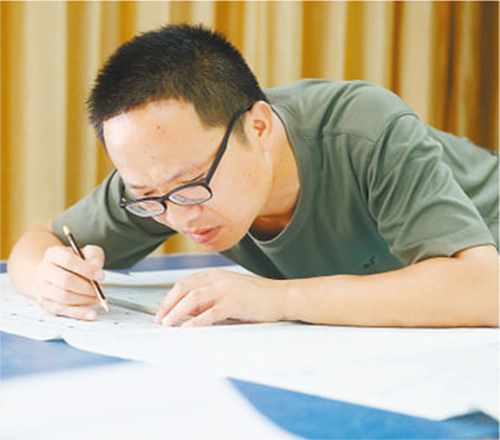 周湘虎正在核對修改施工圖紙。
