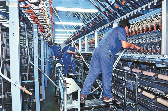 機(jī)器換人提高紡織生產(chǎn)效率。圖為工人在自動生產(chǎn)線上操作。