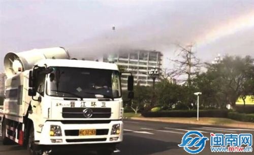 中國僑網(wǎng)抑塵車噴射出的水霧,,經(jīng)陽光折射,,形成一道彩虹。
