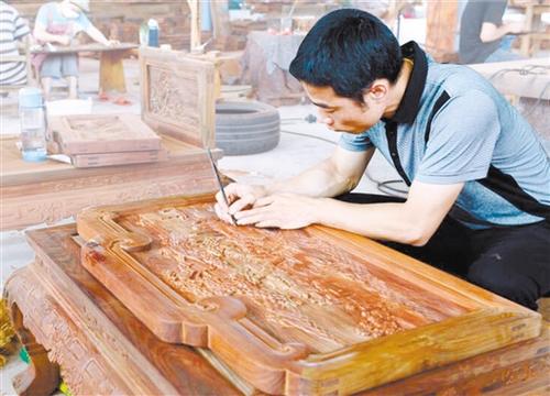 中國僑網(wǎng)李炳祺手工修磨家具上的圖案。陳英 攝