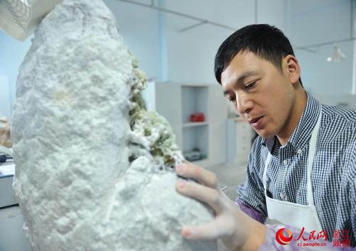中國僑網劉宙正在制作青田石雕,。